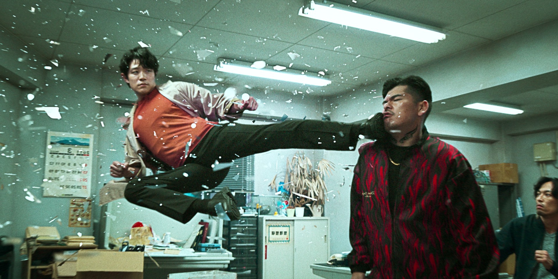 Un hombre flotando en el aire patea a otro hombre en la cara en City Hunter.