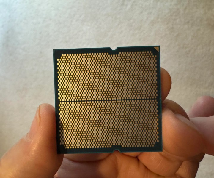 A person is holding the AMD Ryzen 9 9950X3D CPU. The pins are bulging.