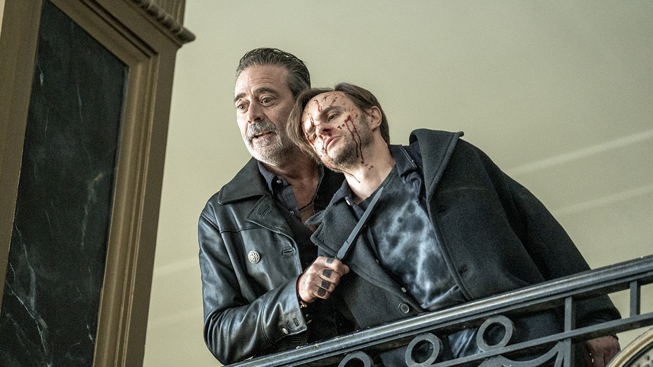Negan holding a knife to a bloody man's throat in The Walking Dead: Dead City.